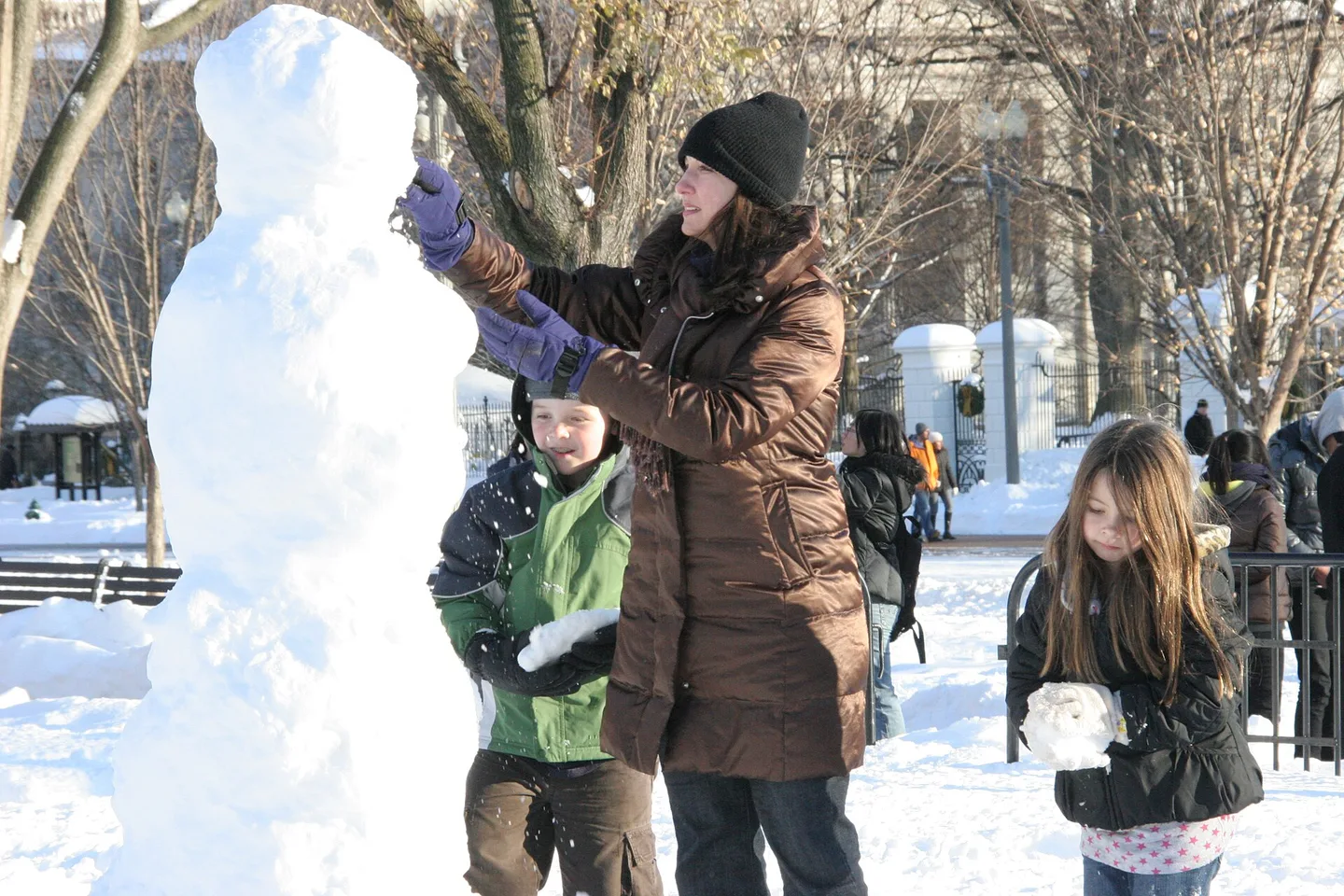 家长带着孩子在雪地里堆雪人