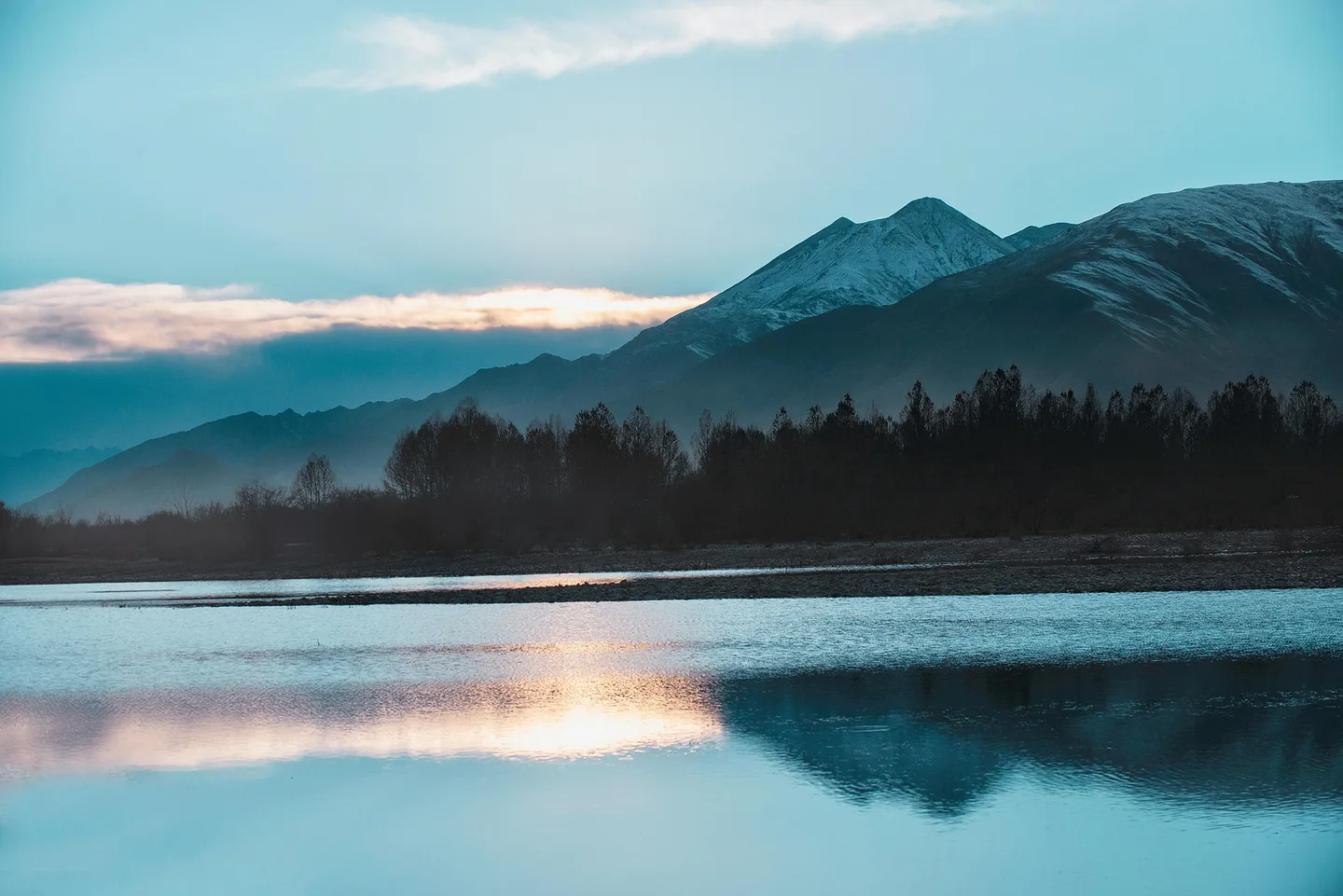 晨曦中雪峰之下的高原湖泊
