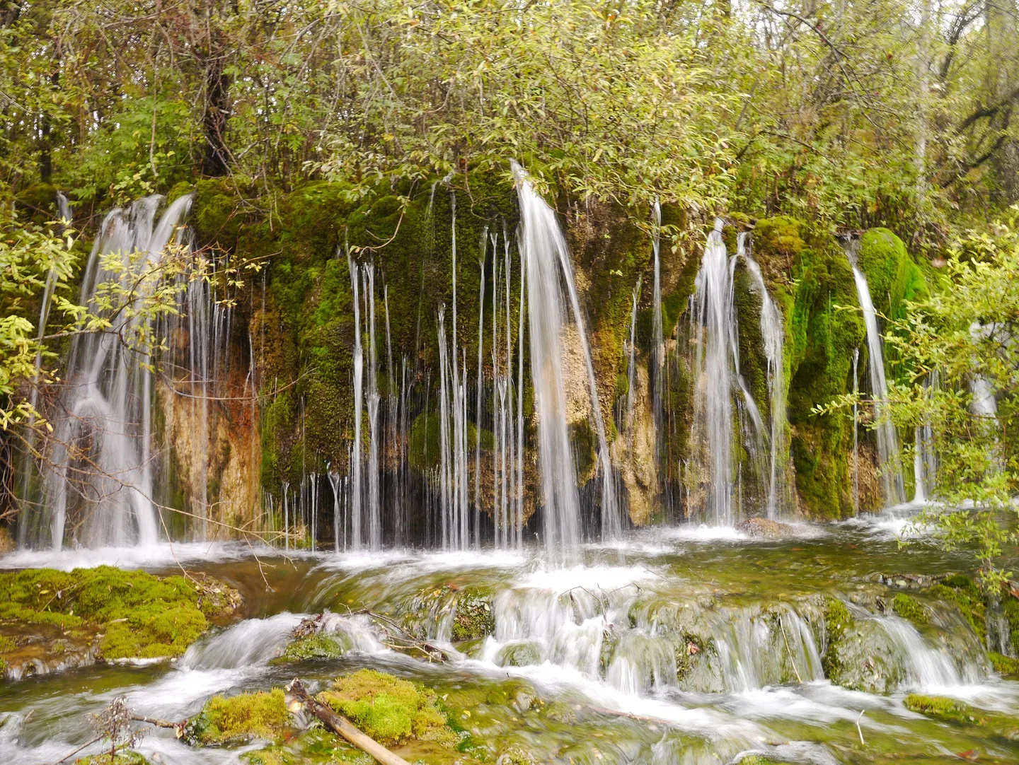 山间瀑布飞流而下，水雾弥漫的山水画面